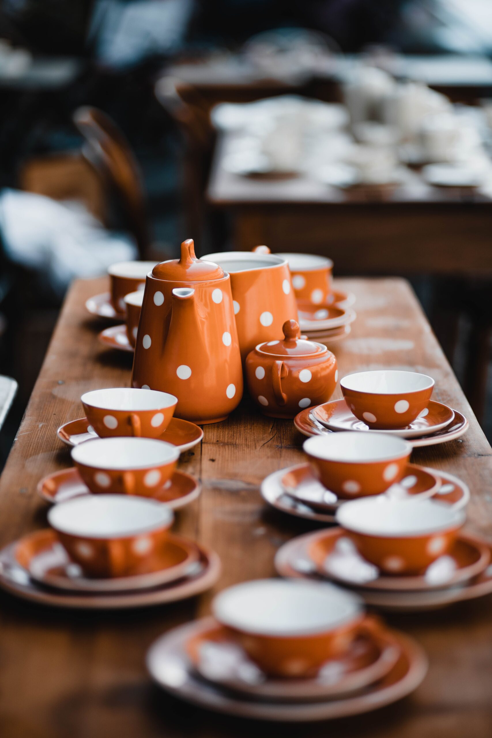 Charming orange polka dot tea set with teapot, cups, and saucers on a wooden table.
